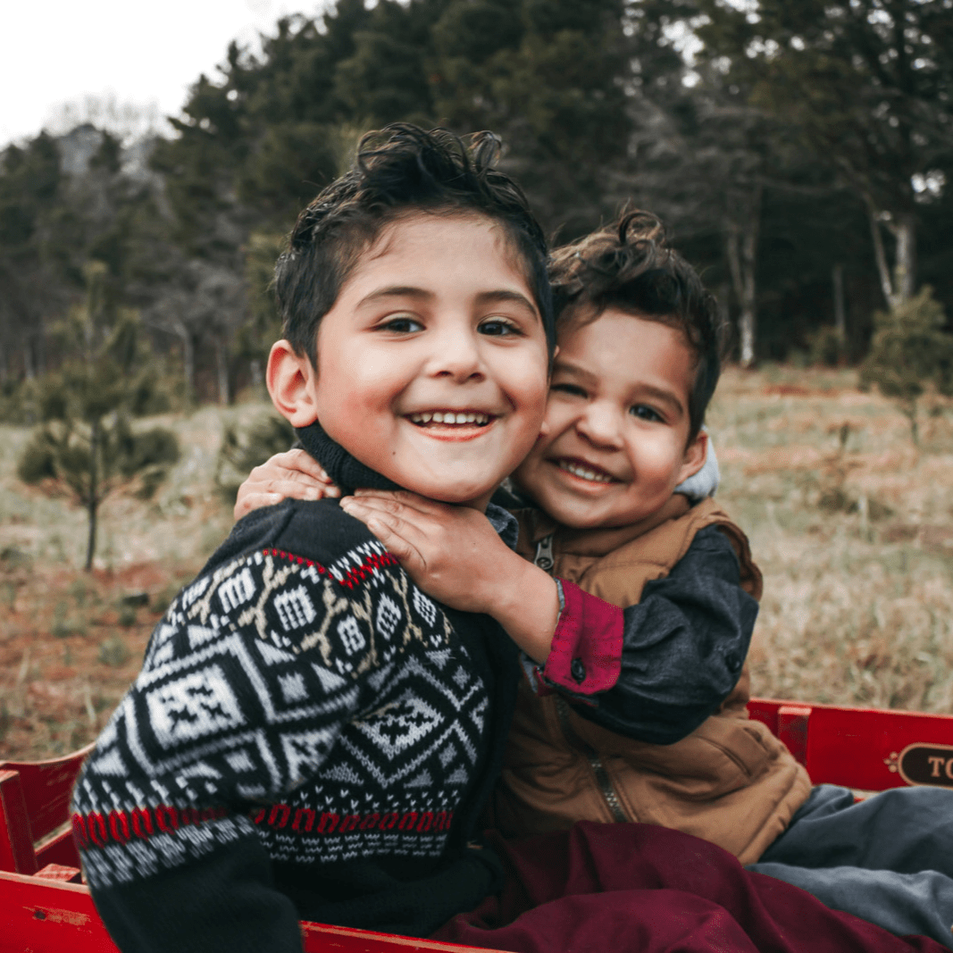 Two little boys smiling and hugging